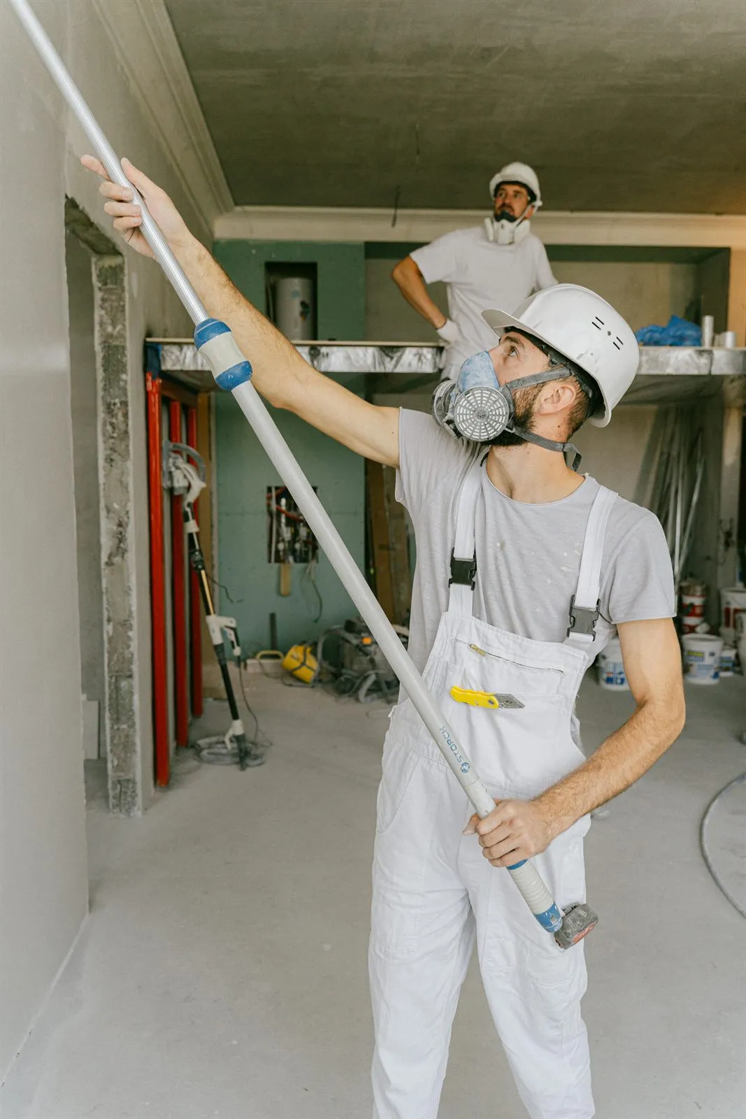 Painters working from a lift in a large interior space