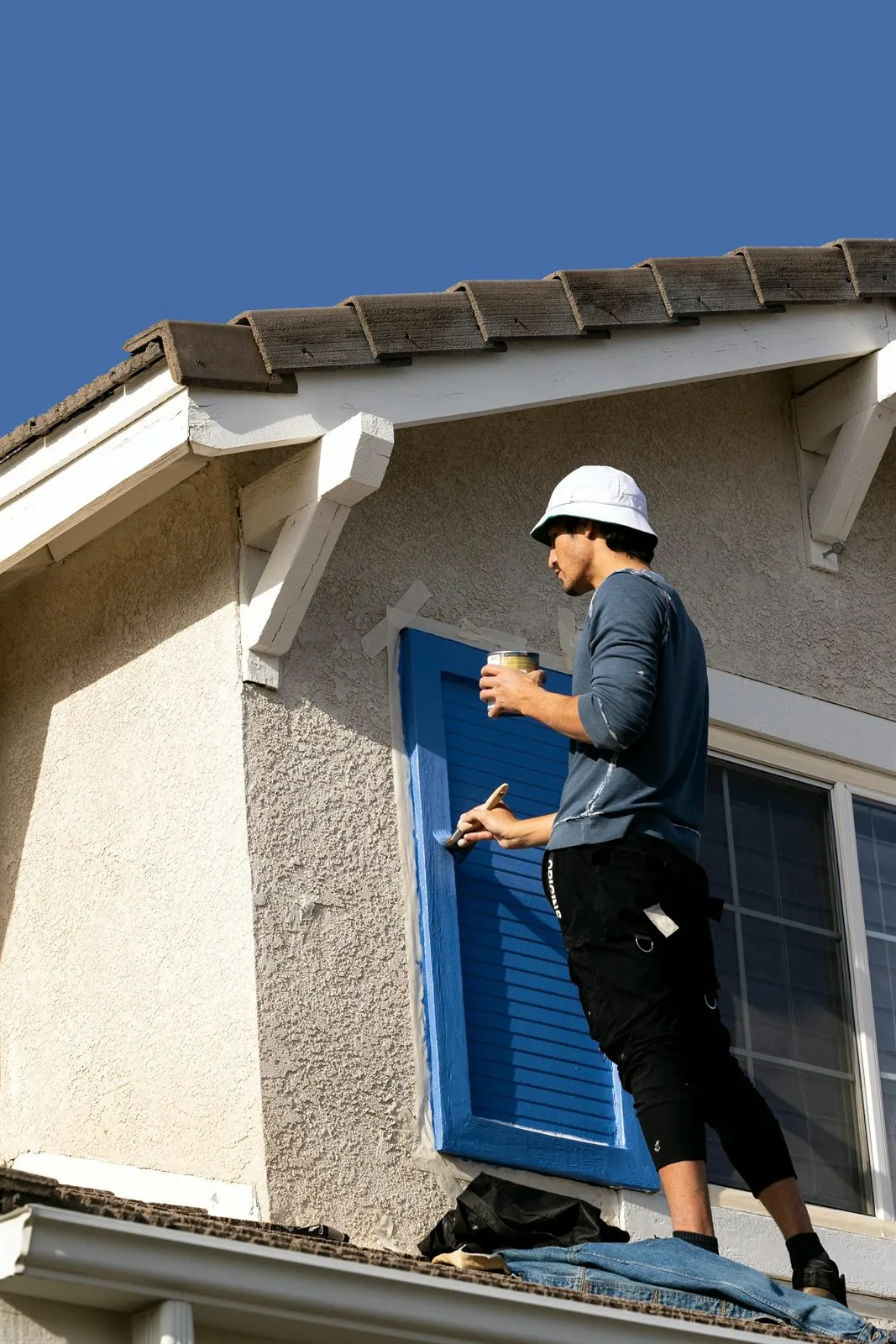 Painter applying blue exterior trim paint on a Hampton Roads home