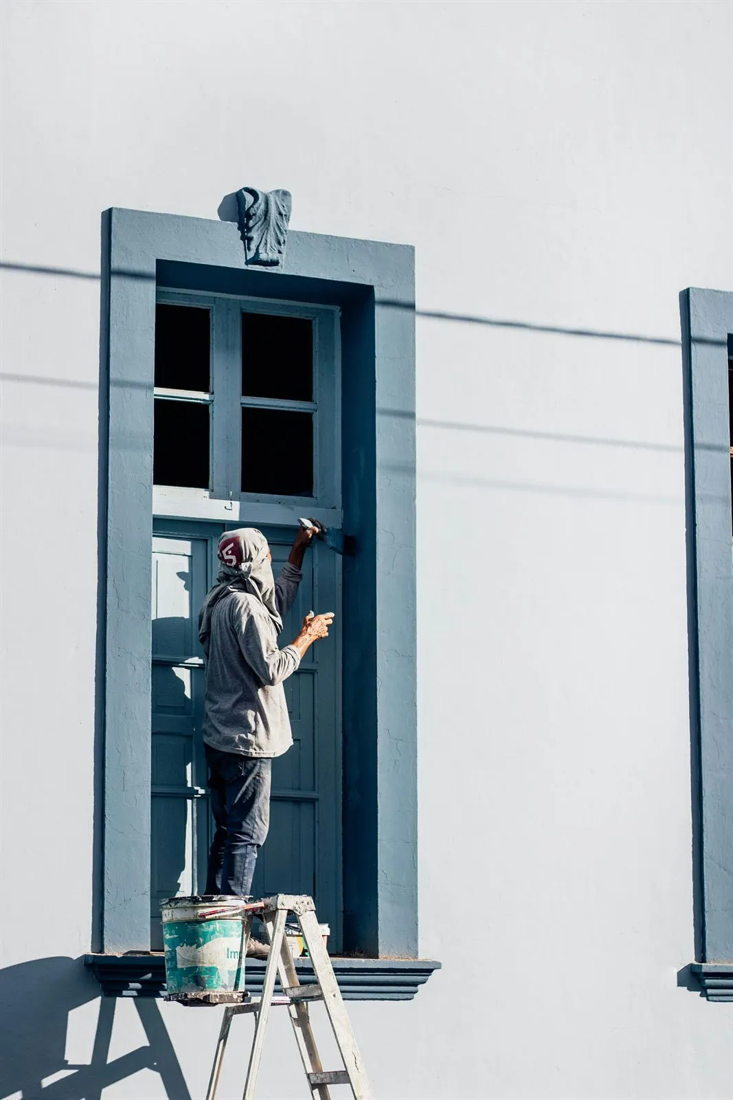 Painter applying blue paint around an exterior window