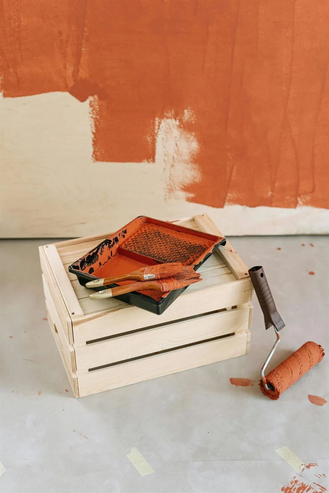 Paint tray and roller beside a freshly painted wall