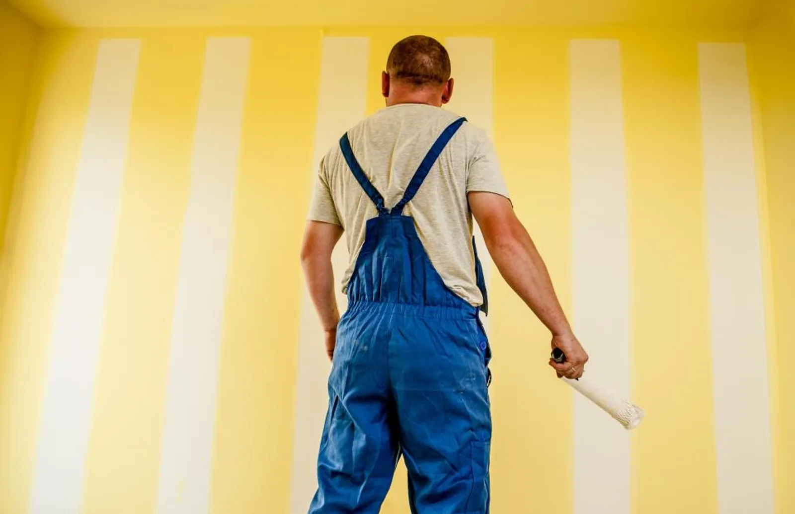Painter rolling fresh paint onto an interior wall.